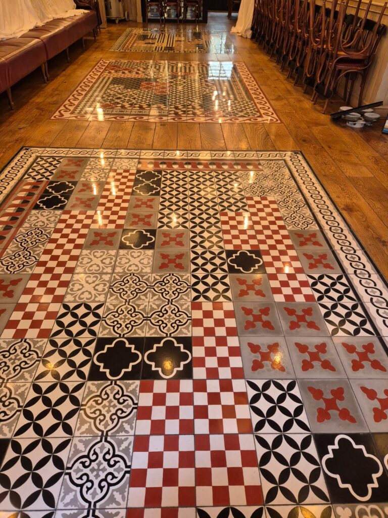 Décoration de Sol : Parquet et Carreaux de Ciment Colorés Sol en bois avec tapis de carreaux de ciment colorés aux motifs géométriques variés dans un restaurant.